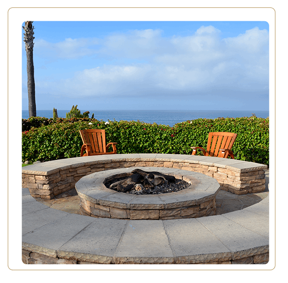 Outdoor patio gas fueled fireplace or firepit covered in stone